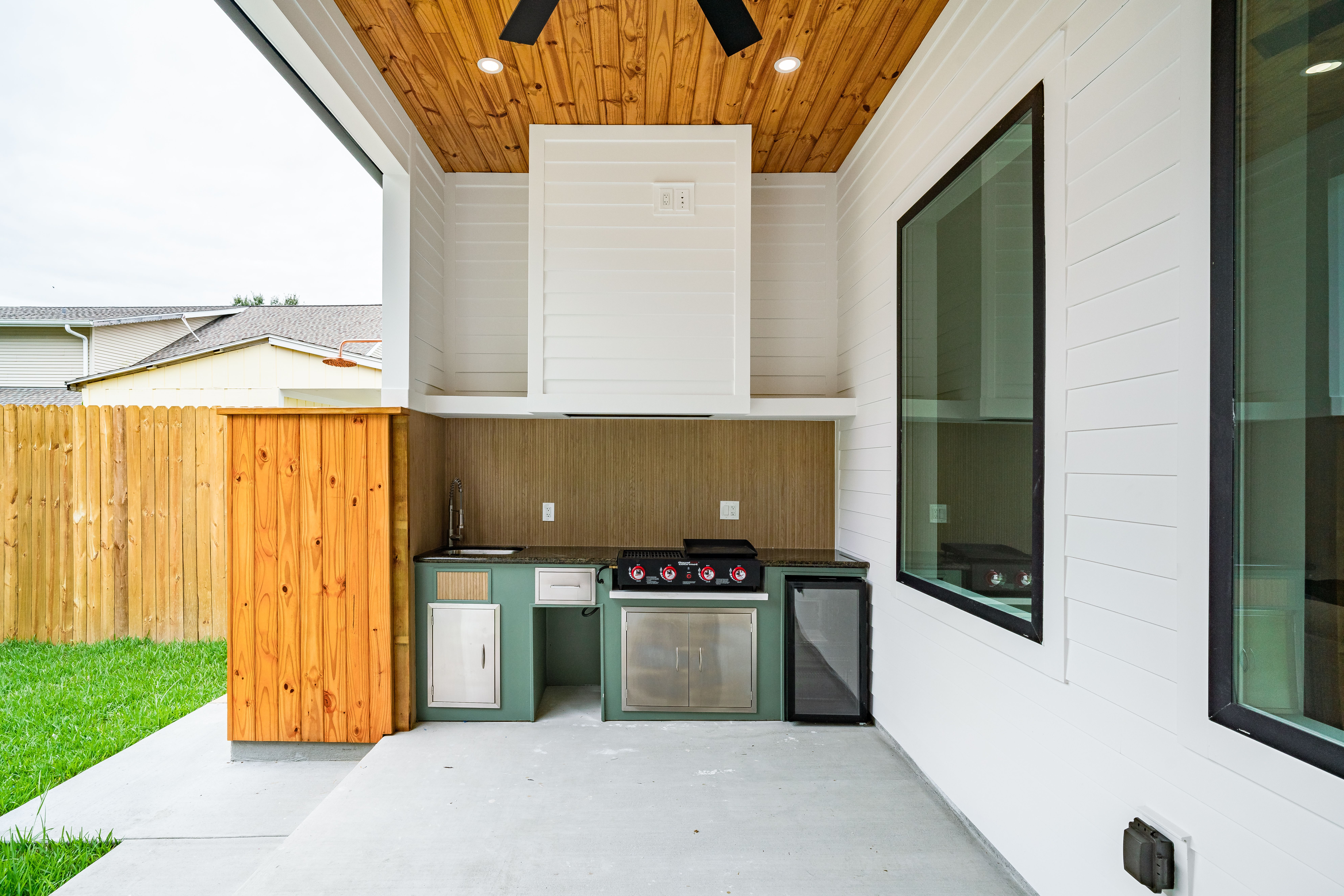 Sleek backyard outdoor kitchen with a built-in barbecue and refrigerator