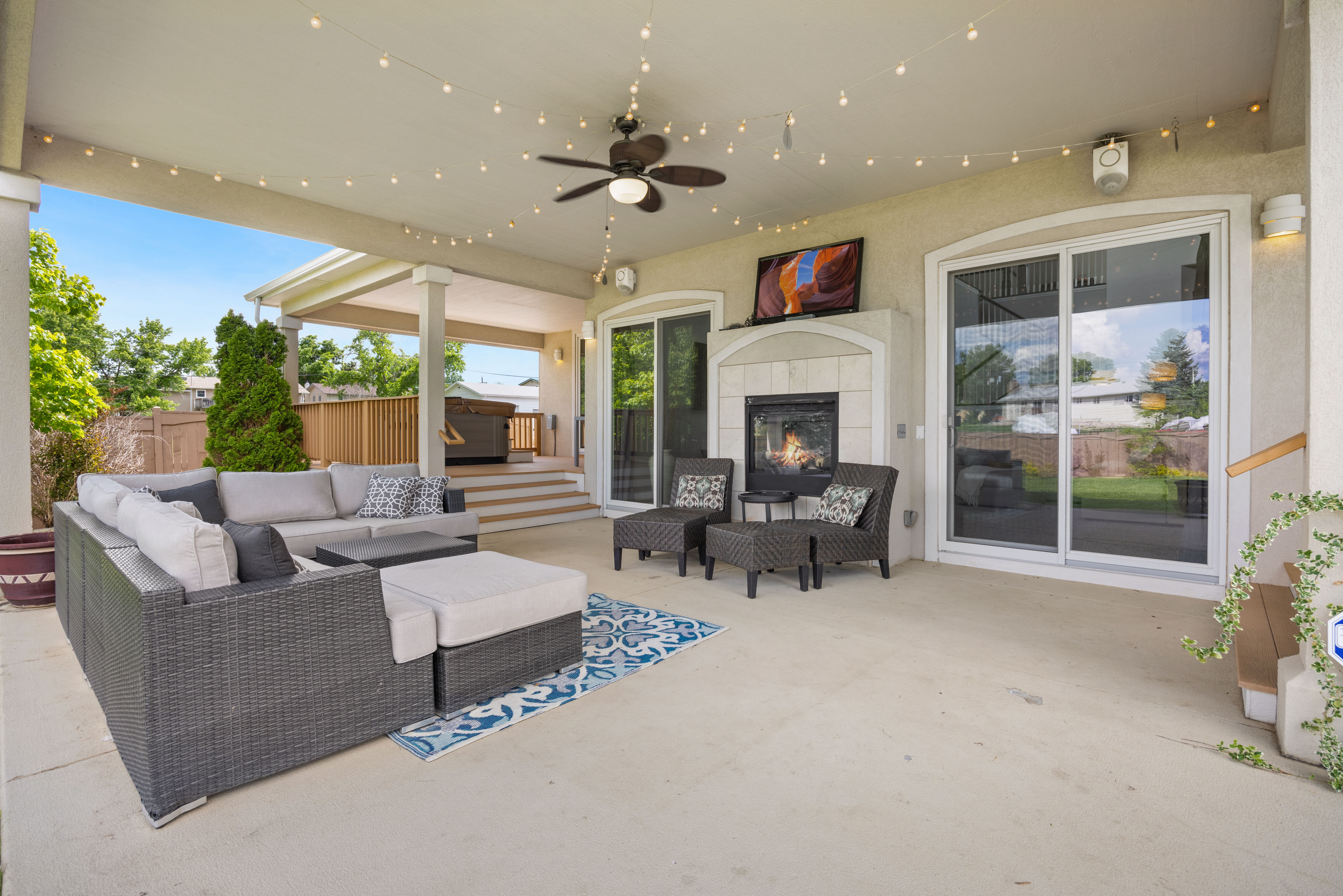 Luxury outdoor patio with a fireplace, modern seating, and ambient string lights